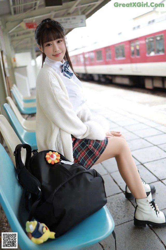 A woman sitting on a bench at a train station.