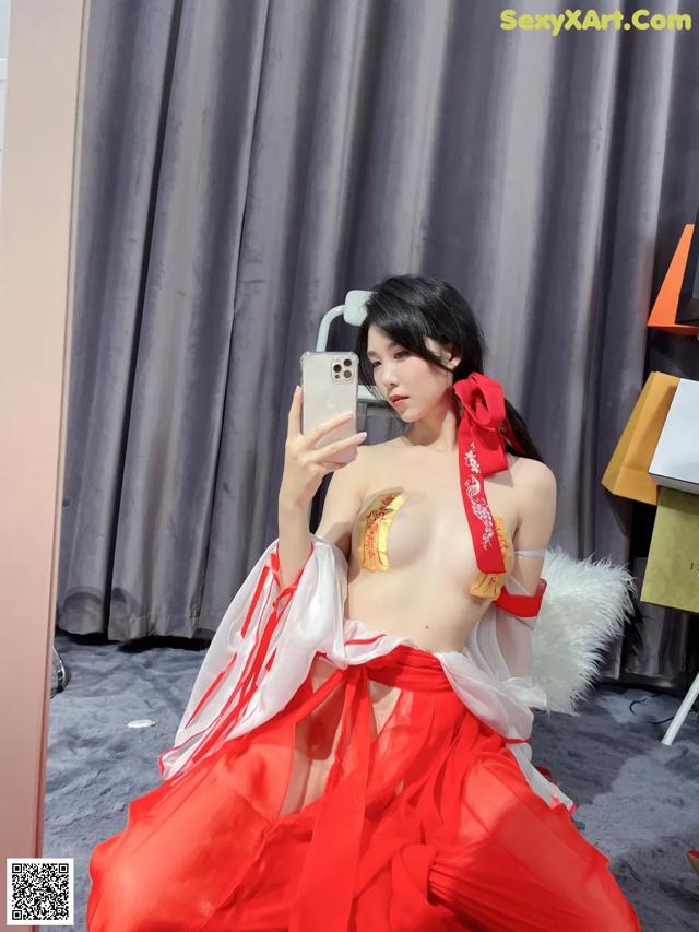 A woman in a red and white dress taking a selfie.