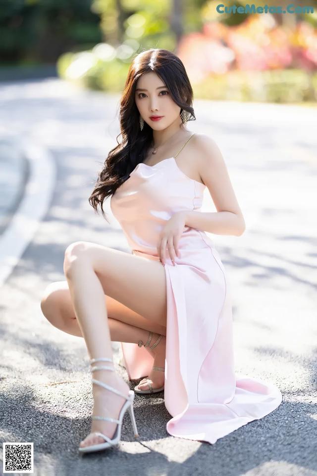A woman in a pink dress sitting on the ground.