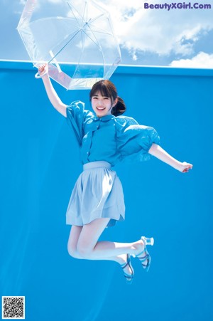 A woman jumping in the air holding an umbrella.