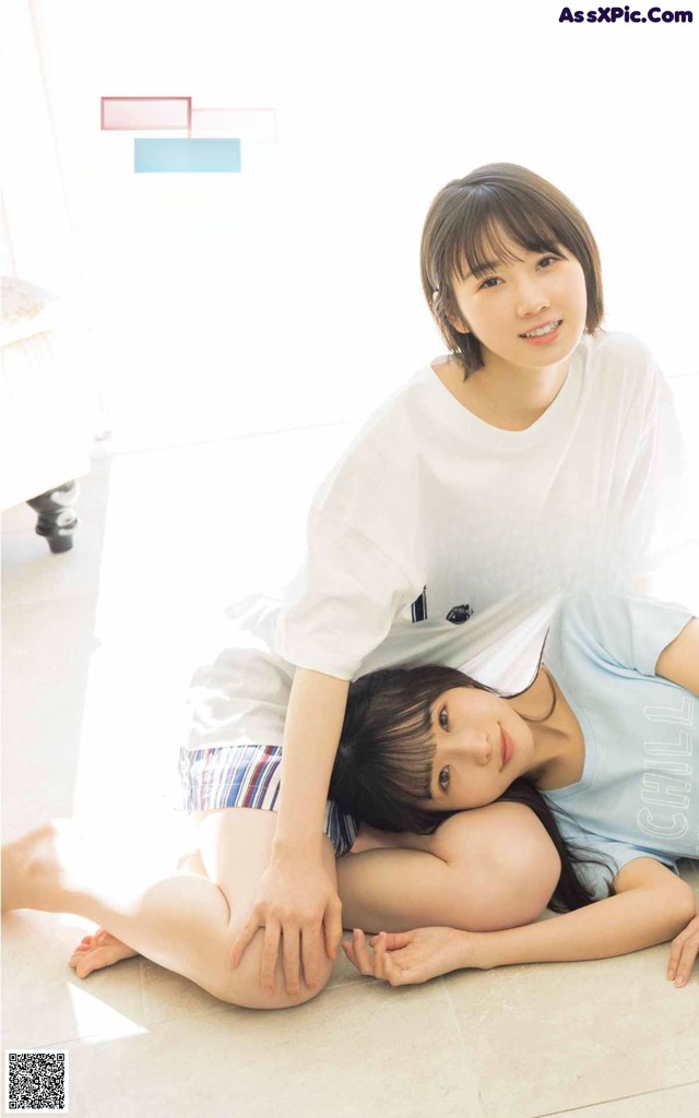 A couple of young women laying on the floor together.