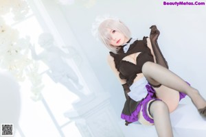 A woman in a black and white maid outfit posing for a picture.