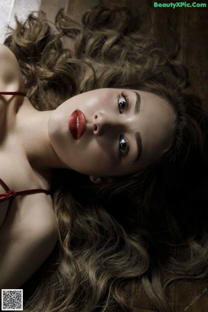 A naked woman laying on a bed next to a window.