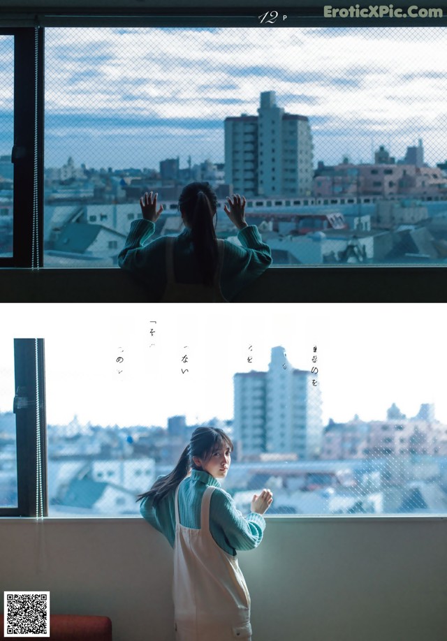 A woman standing in front of a window looking out at a city.