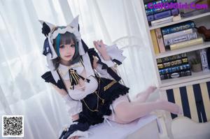 A woman in a maid outfit sitting on a bed.