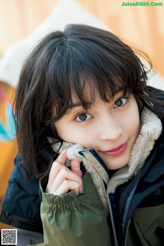 A young woman in a green jacket is posing for a picture.