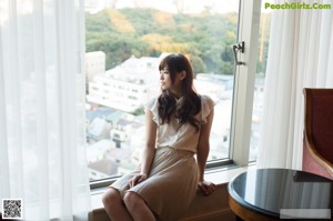 A woman in a white lingerie sitting on a bed.