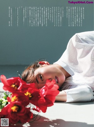 A woman laying on the ground next to a bunch of flowers.