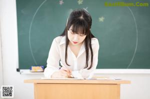 A woman sitting at a desk with a ruler in front of her.