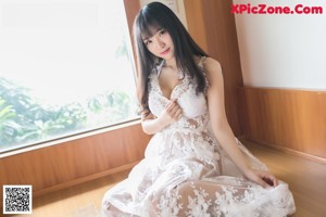A woman in a white dress sitting on a window sill.