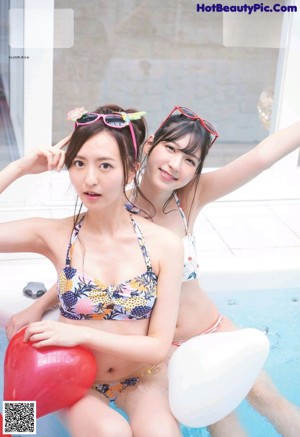 A couple of women standing next to each other in a pool.