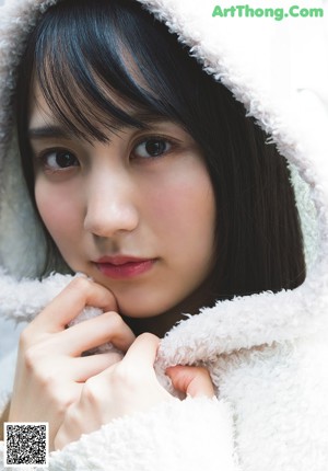 A woman in a white fur coat sitting on a window sill.