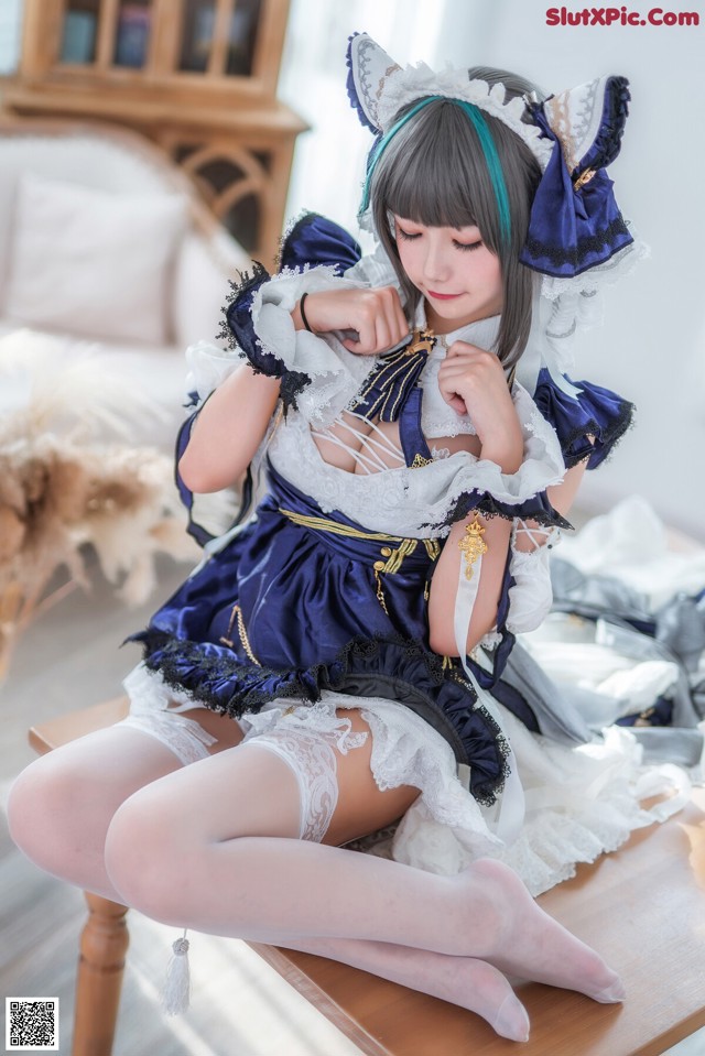 A woman in a blue and white dress sitting on a table.