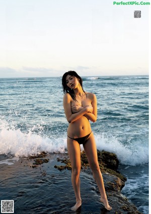 A woman in a pink bikini laughing on the beach.