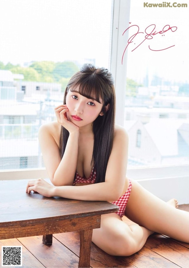 A woman in a red and white bikini sitting on a wooden table.