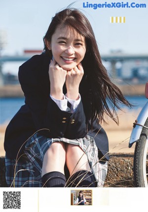 A woman in a white shirt and blue skirt sitting on a red chair.