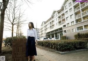 A woman in a white shirt and blue pleated skirt.